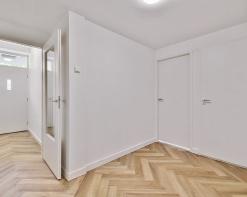 an empty interior area with white walls and laminate flooring