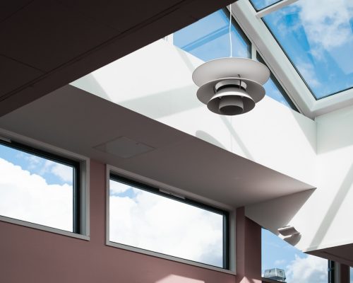 A low angle shot of a lamp hanging inside a building with a glass ceiling